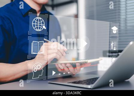 Online education and e-learning concept. Man taking notes while using laptop with online education icon, learning, knowledge sharing, educational tool Stock Photo