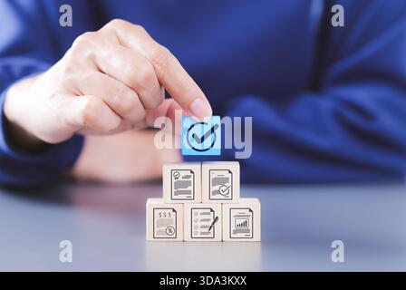 Document review process and quality control concept. Hand placing checkmark. wooden blocks document icons, symbolizing document verification, Stock Photo