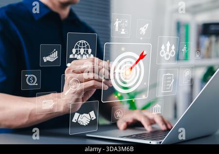 Business goal and target achievement concept. Businessman using laptop interacting with digital interface bullseye target with an arrow, goal setting, Stock Photo
