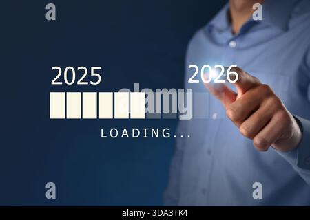 Businessman using virtual screen with loading bar on dark blue background, closeup. New Year 2026 Stock Photo