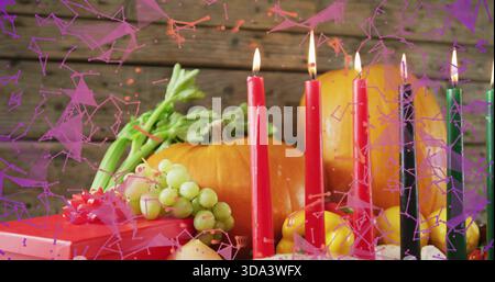 Displaying centered autumnal centerpiece on wood table with lit taper candles, pumpkin, red gift Stock Photo