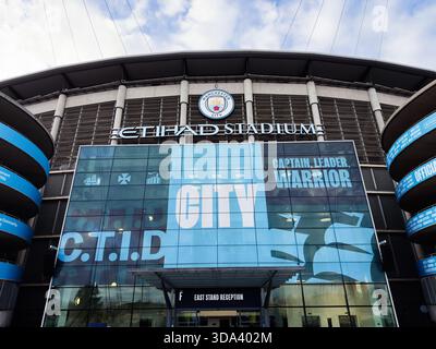 Manchester, UK - November 16, 2025: Exterior view of Manchester Citys Etihad Stadium with large blue banner and modern glass facade. Stock Photo