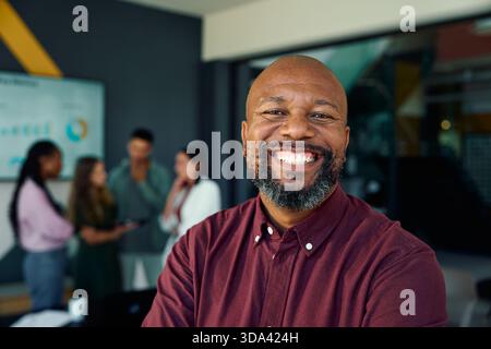 Cheerful mature black businessman standing in meeting room at workplace Stock Photo