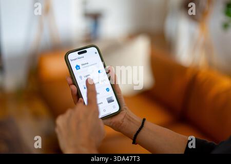 Woman interacting with a smartphone app, effortlessly managing lights and thermostat settings in a modern smart home environment Stock Photo