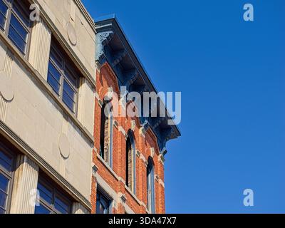 Ornate cornice on late 19th century brick building beside early 20th century Art Deco facade Stock Photo