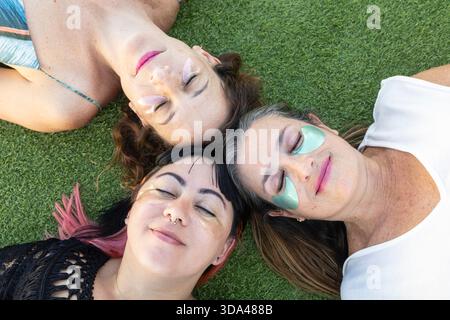 Three beautiful young women wearing under-eye patches while enjoying a home beauty care session together. Stock Photo