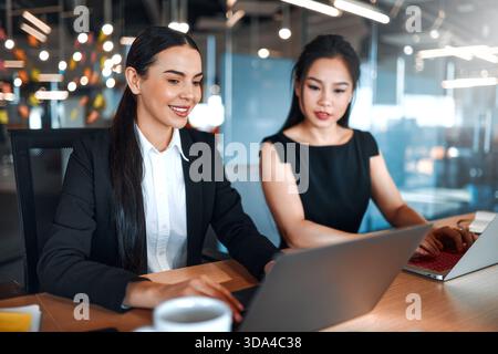A team of young businessmen in formal suits works with laptops while sitting in a modern office. Business women working on laptops and discussing a bu Stock Photo