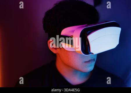 Portrait of teenager with virtual reality glasses and colored lights Stock Photo