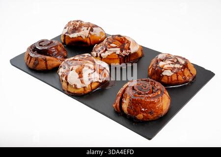 Sweet cinnamon rolls topped with chocolate syrup and creamy frosting Stock Photo