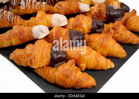 Mini croissants with chocolate and white icing on a black slate tray Stock Photo