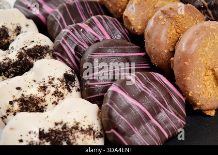 Heart-shaped donuts displaying chocolate, pink, and cream glaze with toppings Stock Photo