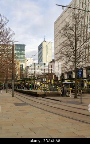 3 December 2025 Commuters wait on the Metrolink tram platforms at St James Square in Central Manchester England. The tall skyscapers that are a featur Stock Photo