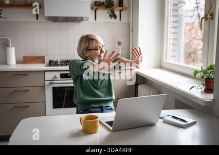 Happy smiling businesswoman taking break from work on laptop, smiling and stretching arms and palms. Stock Photo