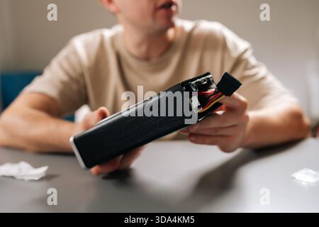 Cropped shot of technician working with electronic device, holding computer hardware with exposed cooling fan, performing repairs and maintenance on Stock Photo