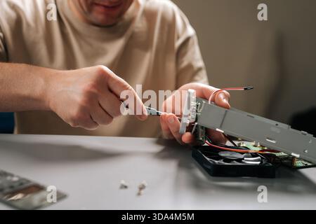 Close-up of man focusing on repairing internal computer hardware components with screwdriver, demonstrating expertise in electronics maintenance and Stock Photo