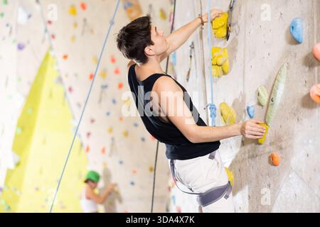 Determined young man doing his best at climbing artificial wall Stock Photo