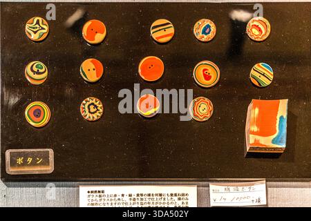 Exhibit featuring traditional Japanese tsuishu buttons (����ܥ���): formed on glass plates by applying many layers of red, blue, green and yellow urushi lacquer, then removed from the glass and finished by hand; Price: 14,000 yen per piece. Shiojiri, Nagano Prefecture, Japan Stock Photo