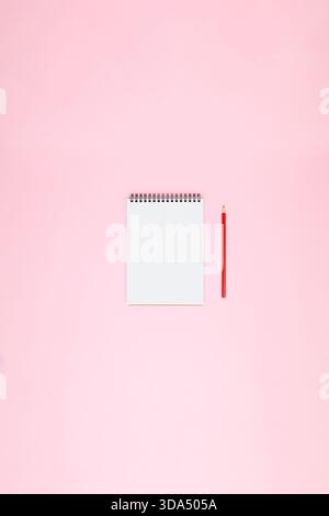 Blank white open spiral notebook with red pencil on soft pink background with wide copy space for planning, notes, wish lists, creative layouts and minimal design projects Stock Photo