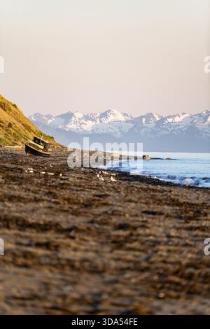 Point Inlet Alaska Boat on Anchor Point beach on Cook Inlet in the evening light, snowy ...