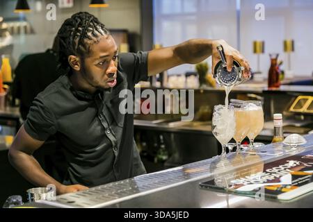 Johannesburg, South Africa - November 15, 2017: African Bartender pouring a Fruity cocktail at bar counter Stock Photo