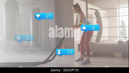 Training woman teal tank maroon leggings using battle ropes boxing gym with reactions, copy space Stock Photo