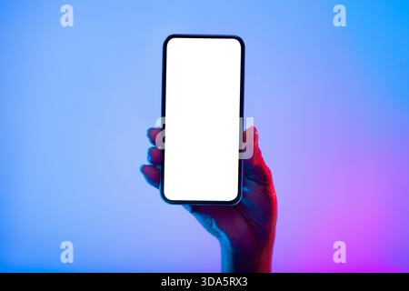 Hand Holding a Smartphone With a Blank Screen Against a Colorful Background Stock Photo