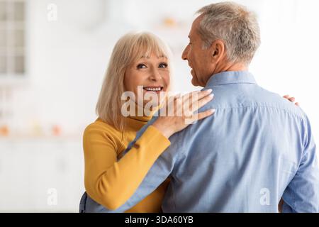 Senior Couple Sharing a Joyful Moment While Dancing in Their Bright Kitchen Stock Photo
