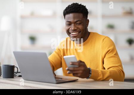 Young black man entrepreneur working on laptop and using cellphone Stock Photo
