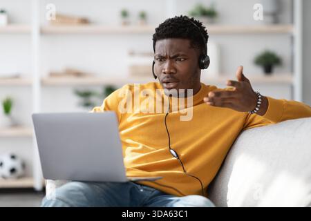 Furious black guy having video call, using laptop at home Stock Photo