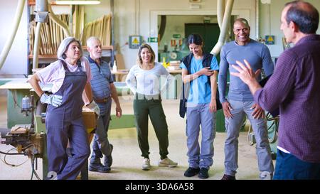 Diverse group of workers listening to a supervisor in workshop Stock Photo