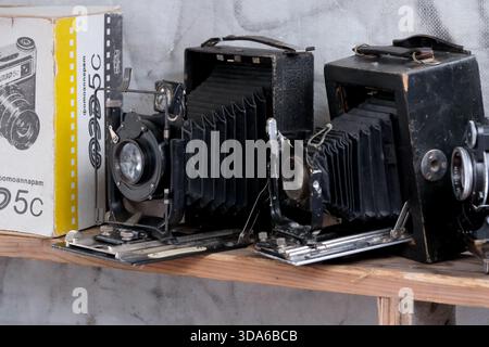 Old cameras rest on a wooden shelf, evoking memories of timeless photography. Stock Photo
