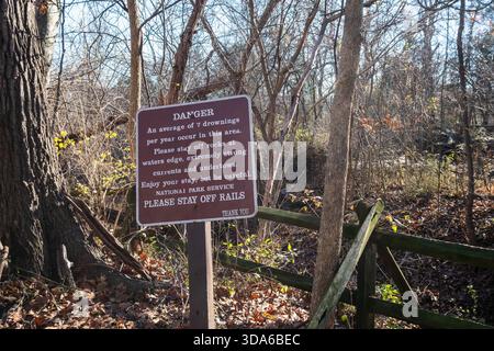 Warning sign about risk of drownings and strong river currents in woodland area at Great Falls Park, Virginia, USA Stock Photo
