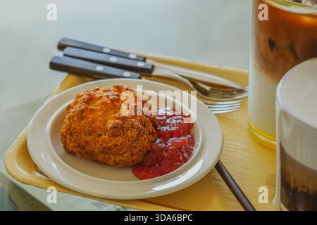 Scone and Strawberry Jam with Cutlery Set Alongside Various Coffee Beverages on a Cafe Tray Stock Photo