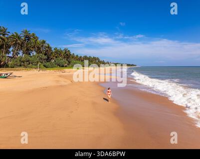 Aerial View of a Young Woman Walking on Orange Sand Beach at Kahandamodara, Southern Sri Lanka Stock Photo