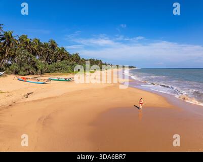Aerial View of a Young Woman Walking on Orange Sand Beach at Kahandamodara, Southern Sri Lanka Stock Photo