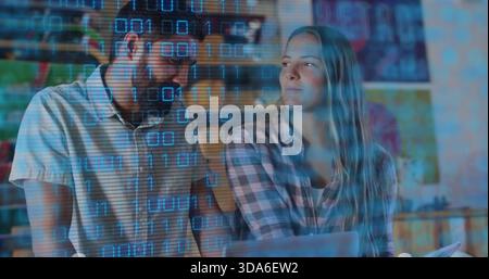 Leaning man in short-sleeve and woman in plaid reviewing code on laptop at desk, binary overlay Stock Photo