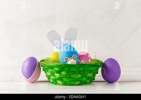 Colorful Easter eggs and basket on a white wooden table for spring celebration Stock Photo