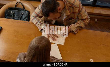 Two colleagues brainstorming ideas in a cozy coffee shop with notebooks Stock Photo
