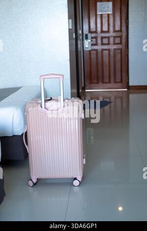 Suitcase standing by the bedside in modern hotel room, showcasing vacation arrival atmosphere Stock Photo