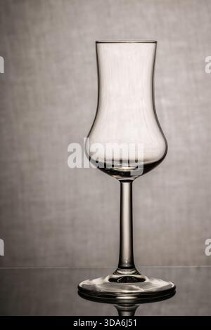 empty brandy glass with reflection on textured gray background Stock Photo