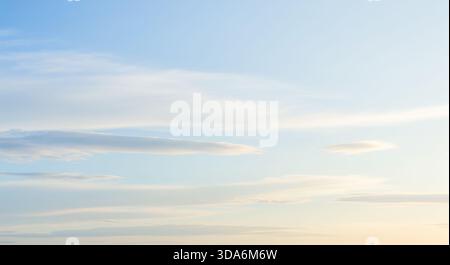 Calm sky at sunset or sunrise with blue and yellow gradient, peaceful evening or morning background with soft clouds and warm light, nature scenery Stock Photo