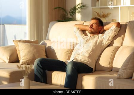 Relaxed man at sunset at home resting sitting on a sofa sitting on a sofa at home Stock Photo