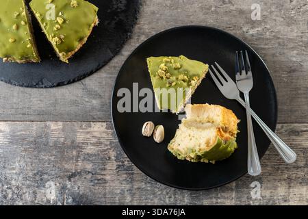 Slice of pistachio cake served on black plate, overhead view Stock Photo