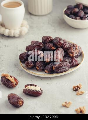 Fresh Medjool dates served on a ceramic plate with a cup of coffee on a bright neutral background. Simple styling and soft natural light create a clea Stock Photo
