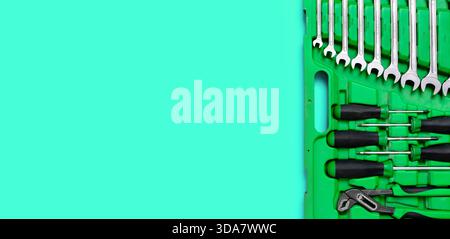 Green set of construction tools: wrenches, adjustable pliers, screwdriver and so on on a red background. Banner with place for text for a hardware Stock Photo