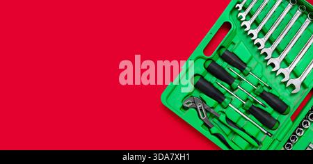 Green set of construction tools: wrenches, adjustable pliers, screwdriver and so on on a red background. Banner with place for text for a hardware Stock Photo