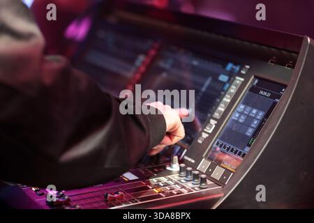 Sound board operator controls digital mixing console during live event. Selective focus. Stock Photo