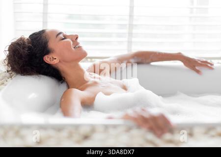 Relaxing in a Bubble Bath at Home During the Evening for a Soothing Self-Care Session Stock Photo
