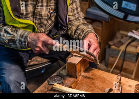 A craftsman’s hands use a bow saw to cut the fine teeth into a block of wood – the first step in the traditional craft of comb-making in Kiso, Nagano Prefecture, Japan Stock Photo