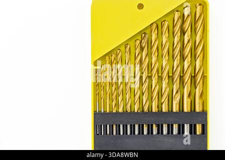 A close-up image shows a set of gold drill bits neatly arranged within a bright yellow case. The drill bits vary in size, showcasing their intricate s Stock Photo